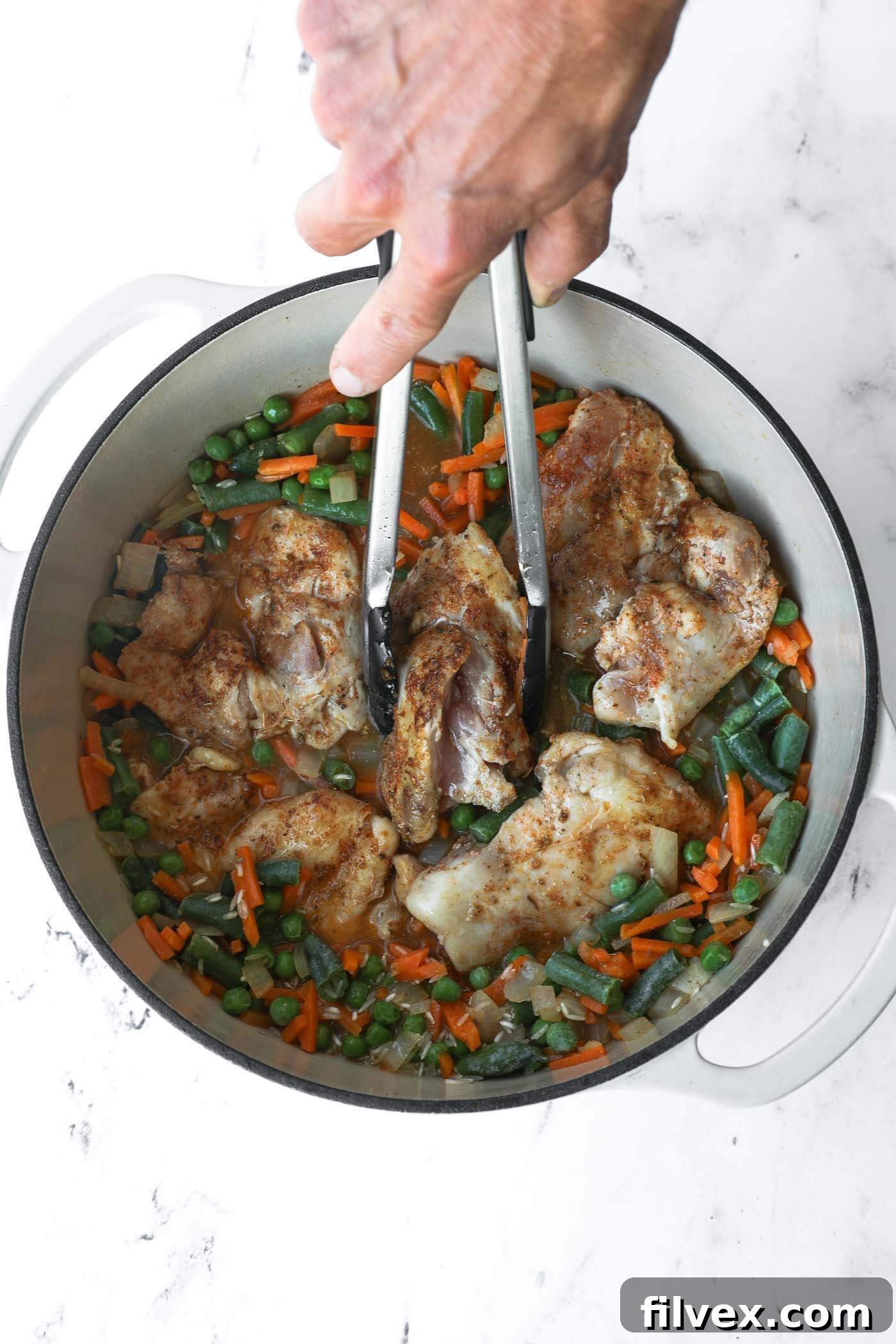 Seared chicken thighs are placed back on top of the rice and vegetable mixture.