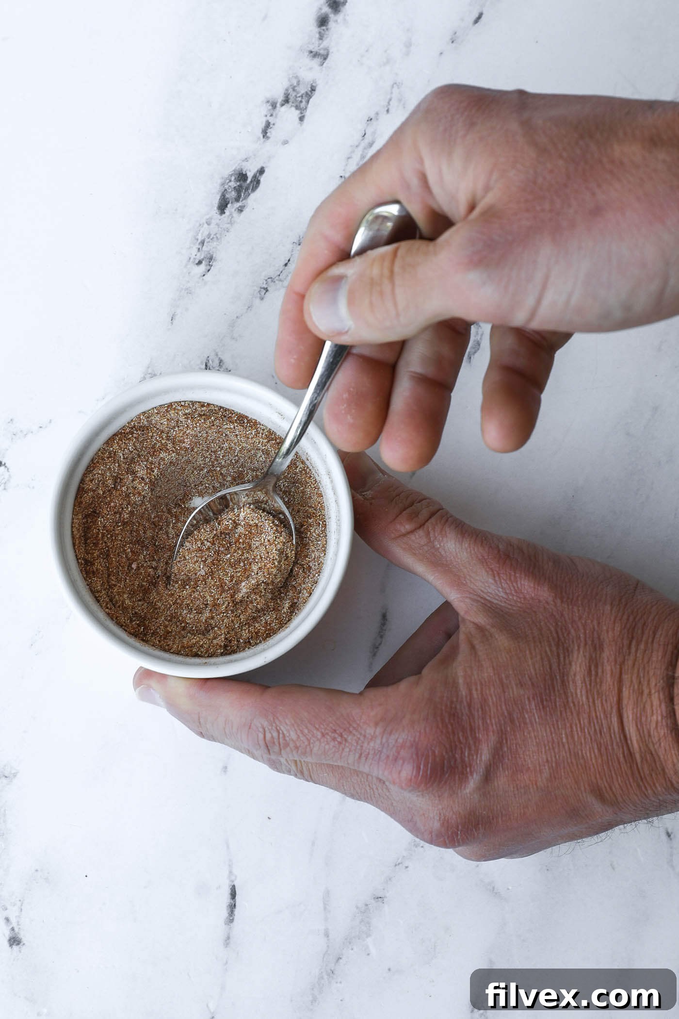 A small bowl holding a vibrant blend of spices for the pulled pork seasoning.