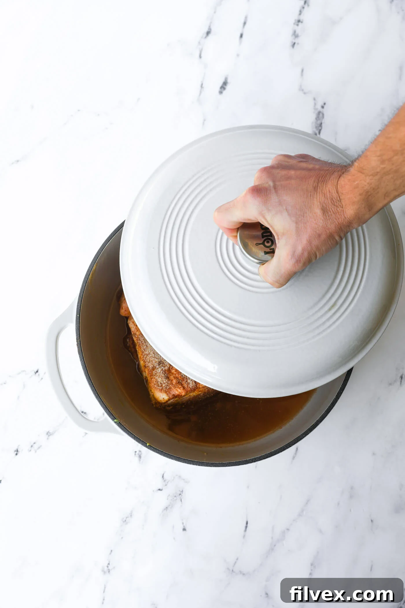 A lidded Dutch oven containing the pork, placed inside a hot oven.