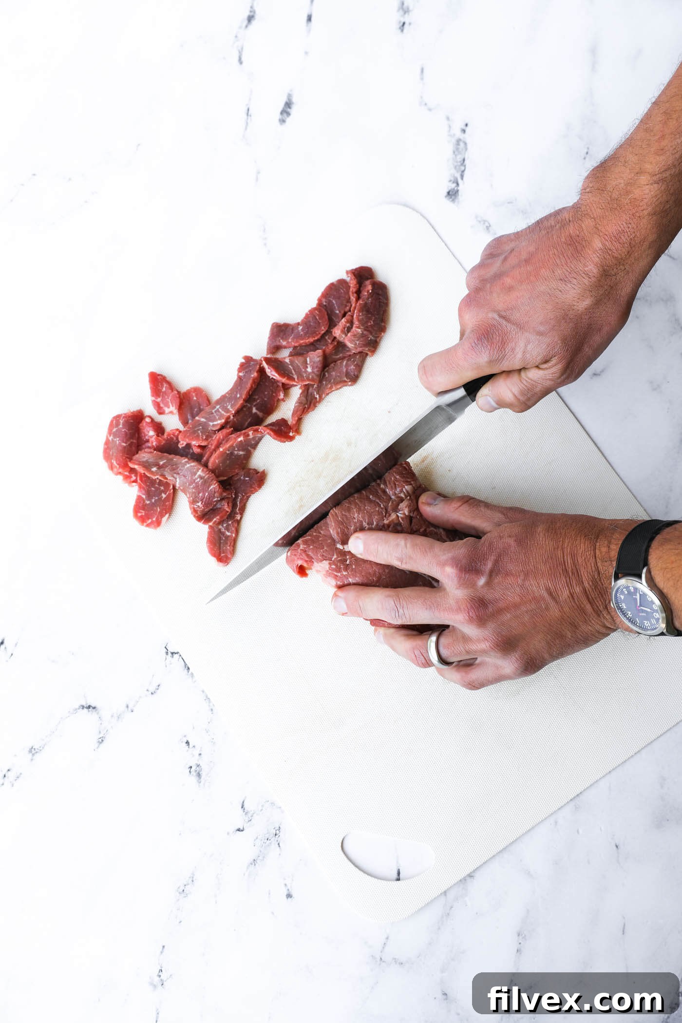 Thinly sliced sirloin steak strips laid out on a cutting board, ready for cooking, a key ingredient for a tender creamy beef dish.