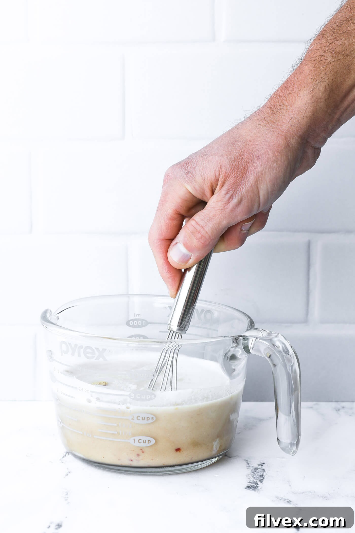 A bowl containing the creamy sauce ingredients, including almond milk, coconut aminos, and spices, whisked together for the mushroom beef skillet.