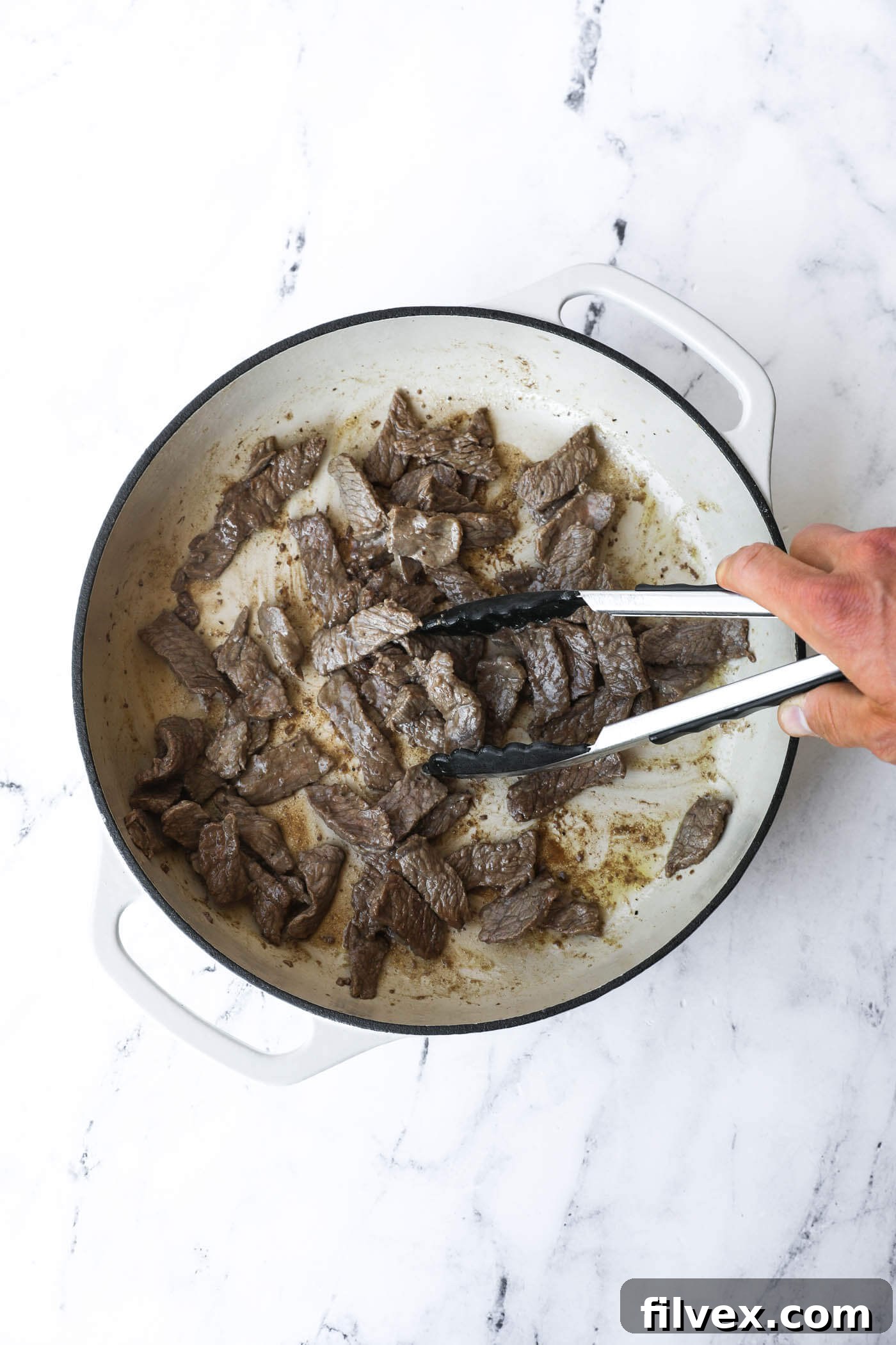 Sirloin beef strips browning in a hot skillet with olive oil, a crucial step for achieving flavor in the creamy beef recipe.