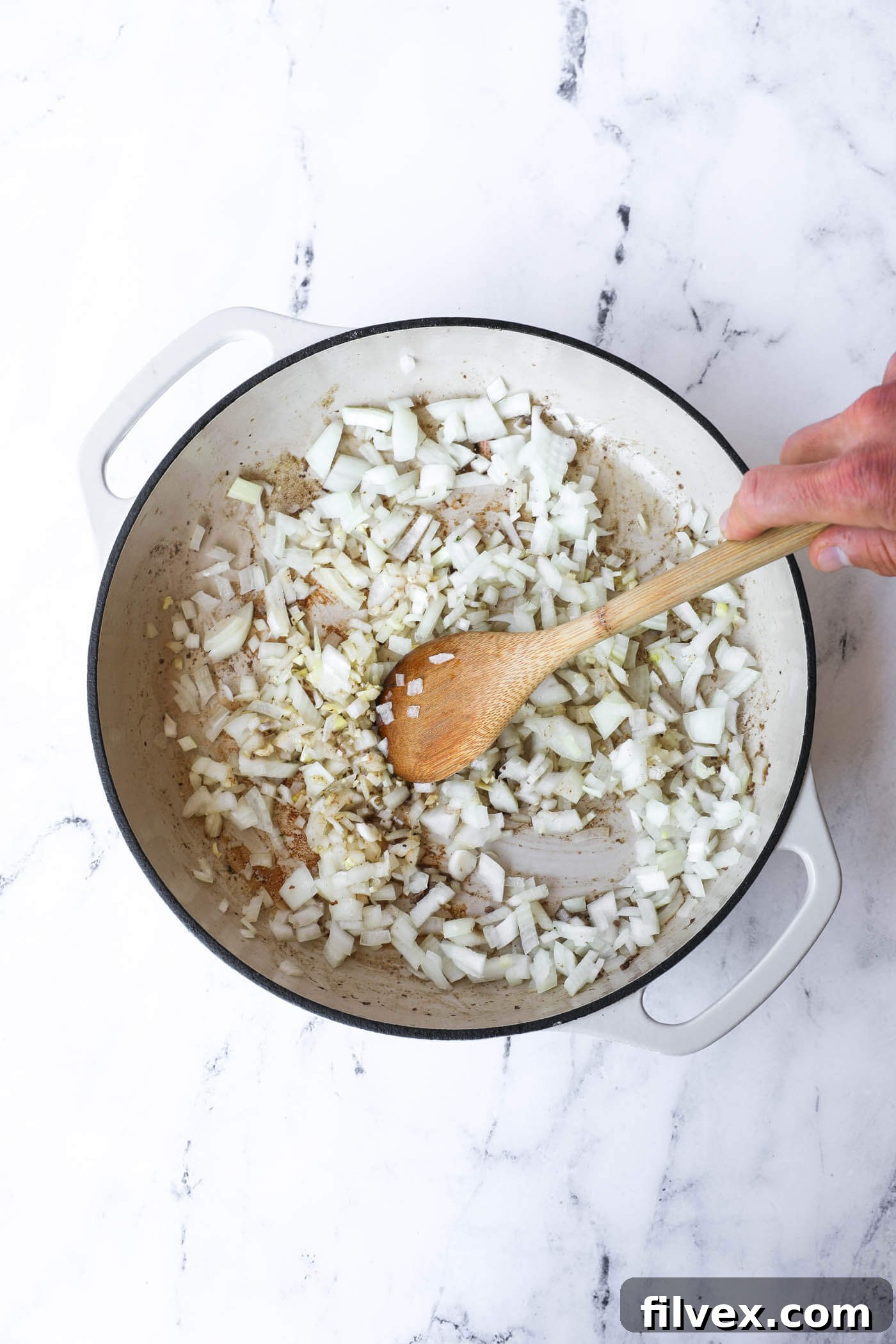 Diced onions and minced garlic sizzling in a skillet, sautéing to become tender and fragrant for the creamy mushroom sauce.