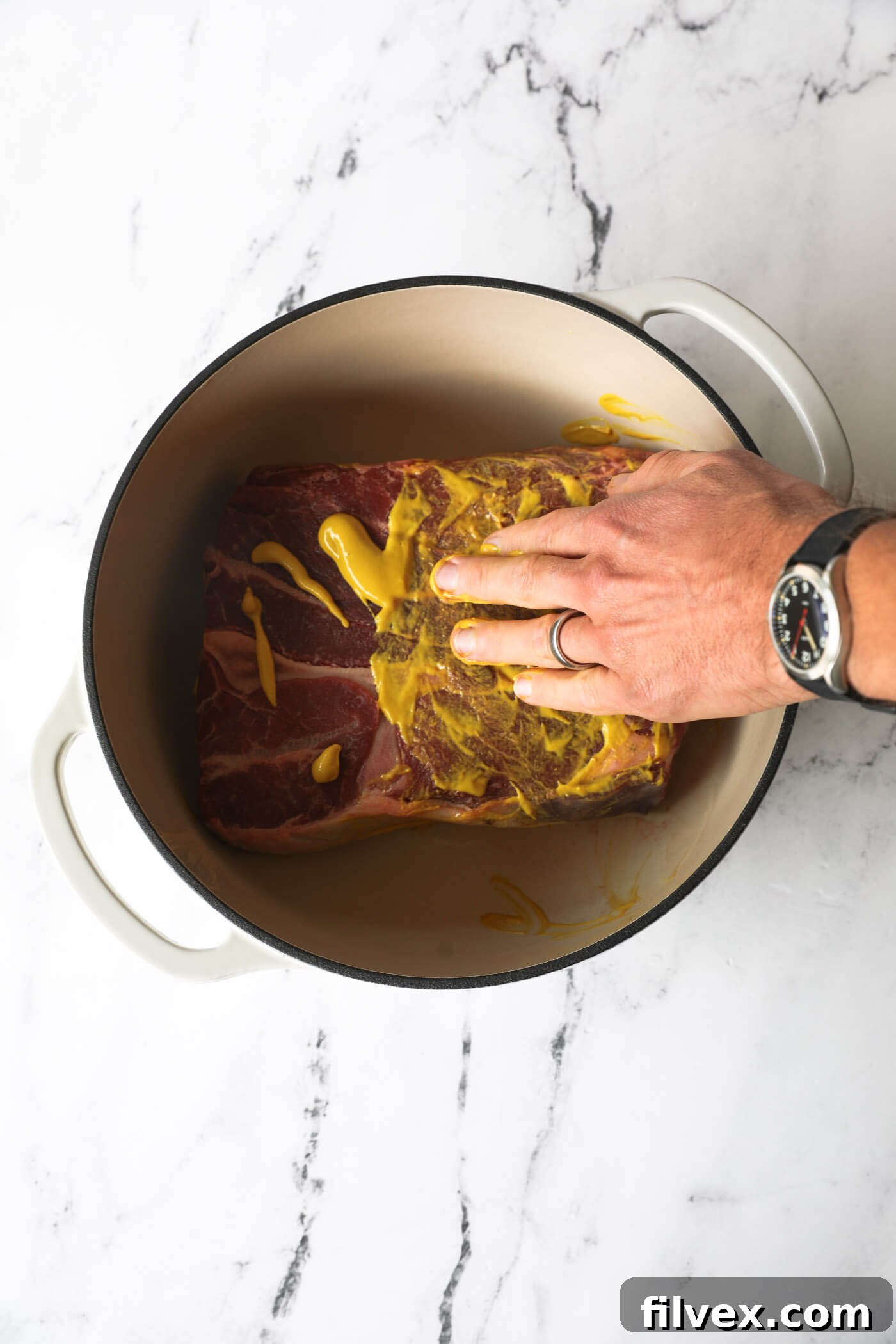 Applying yellow mustard generously to a chuck roast