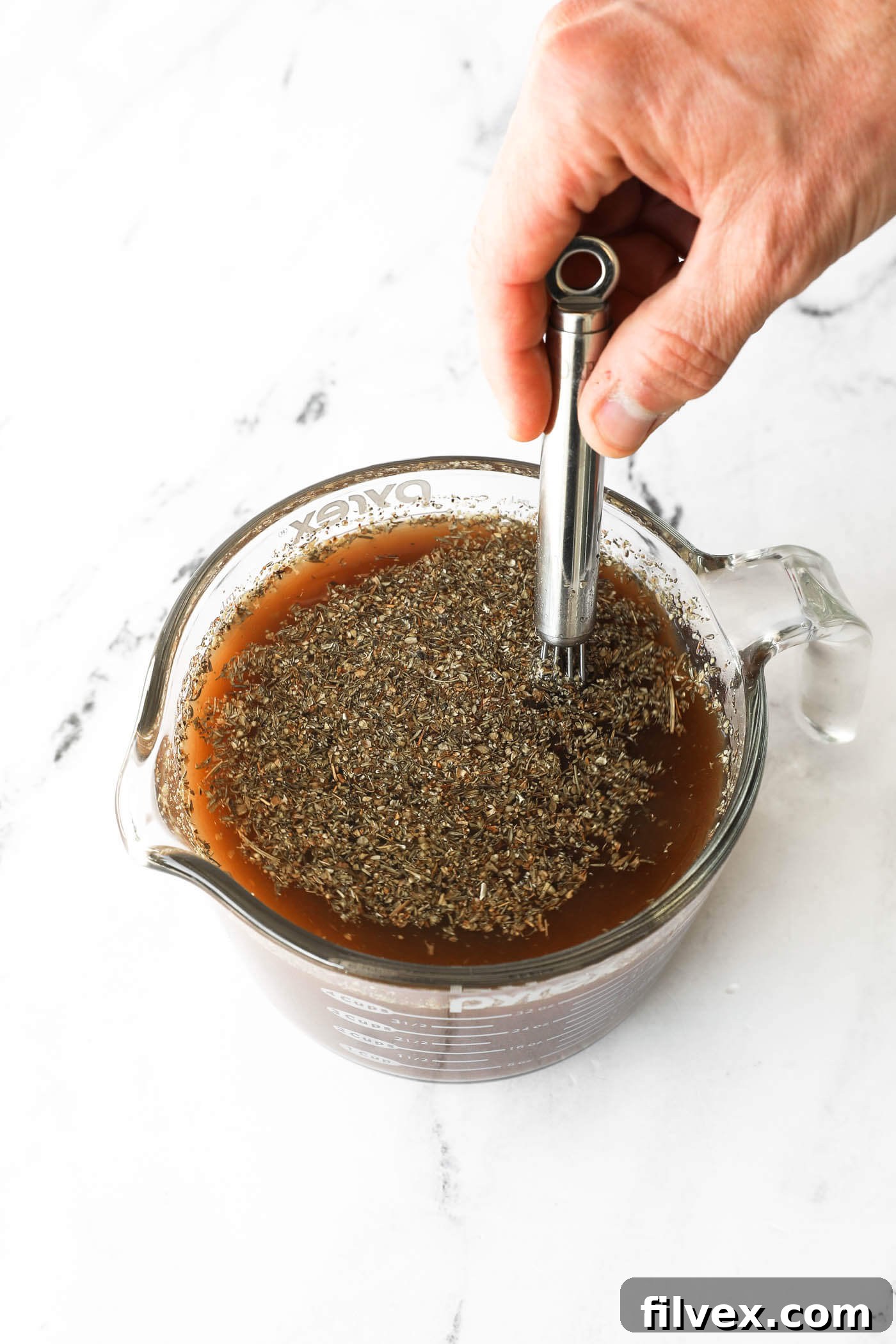 Whisking stew broth ingredients in a large bowl or measuring cup.