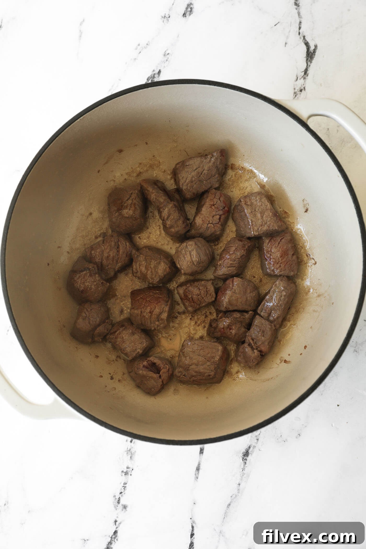 Browning beef cubes in a Dutch oven on medium heat.