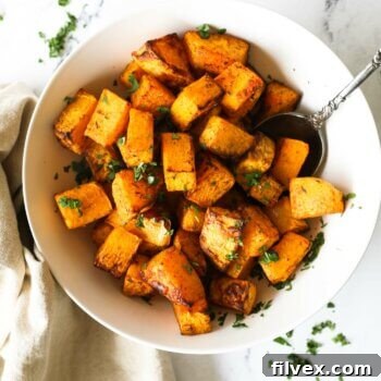 Cooked air fryer butternut squash cubes in a bowl with spoon coming out.