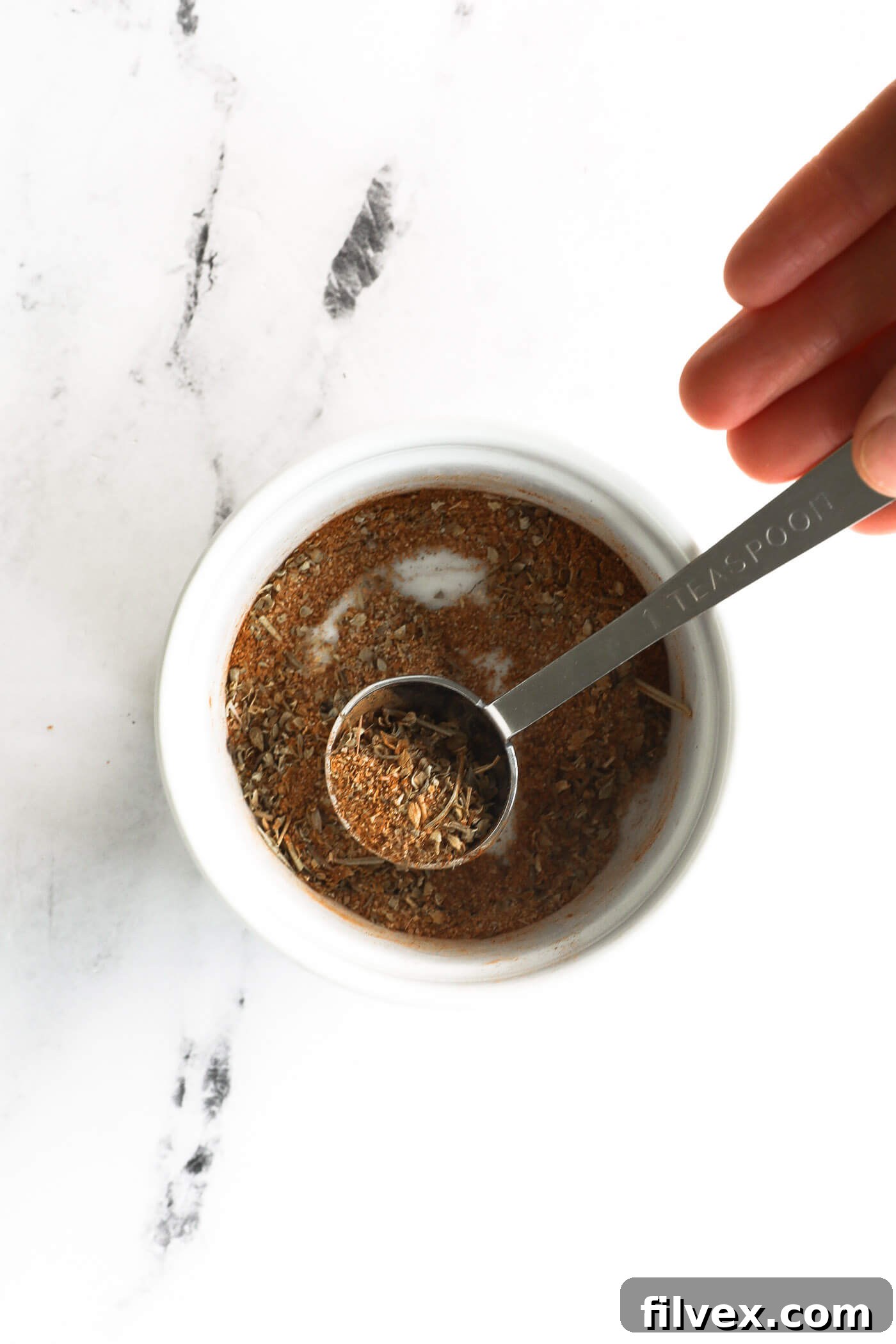 Mixing seasoning blend in a small white bowl.