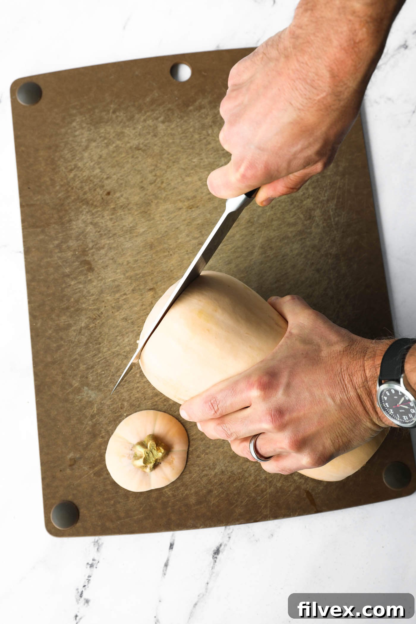 Cutting the ends off a butternut squash on a cutting board.