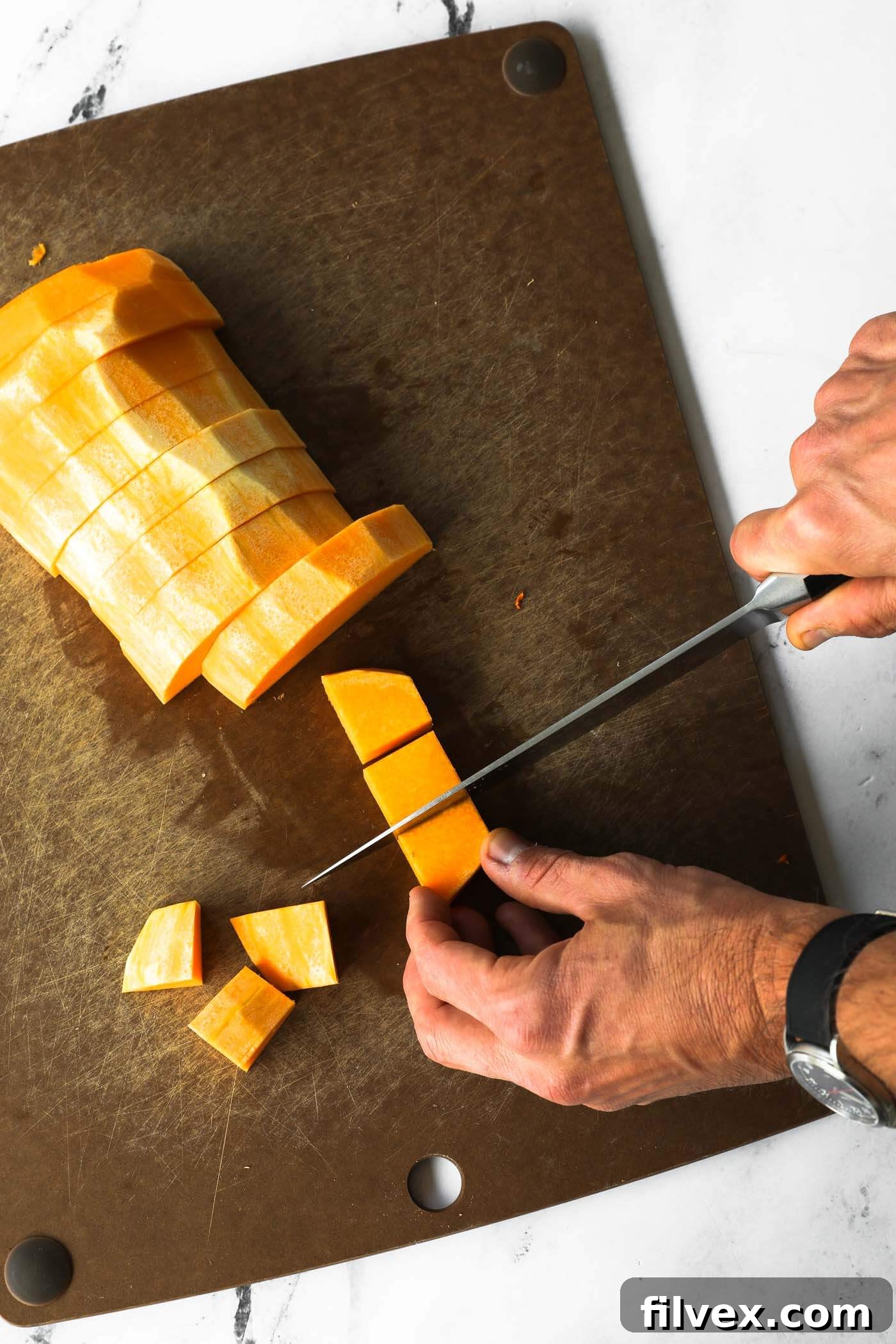 Cubing the butternut squash strips into even pieces.