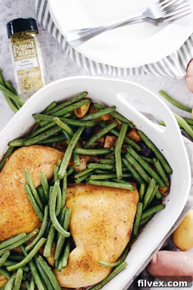 One-Pan Herb Roasted Chicken and Veggies with potatoes and green beans cooking on a baking sheet, showcasing vibrant ingredients. Paleo + Whole30, Gluten-Free + Dairy-Free.
