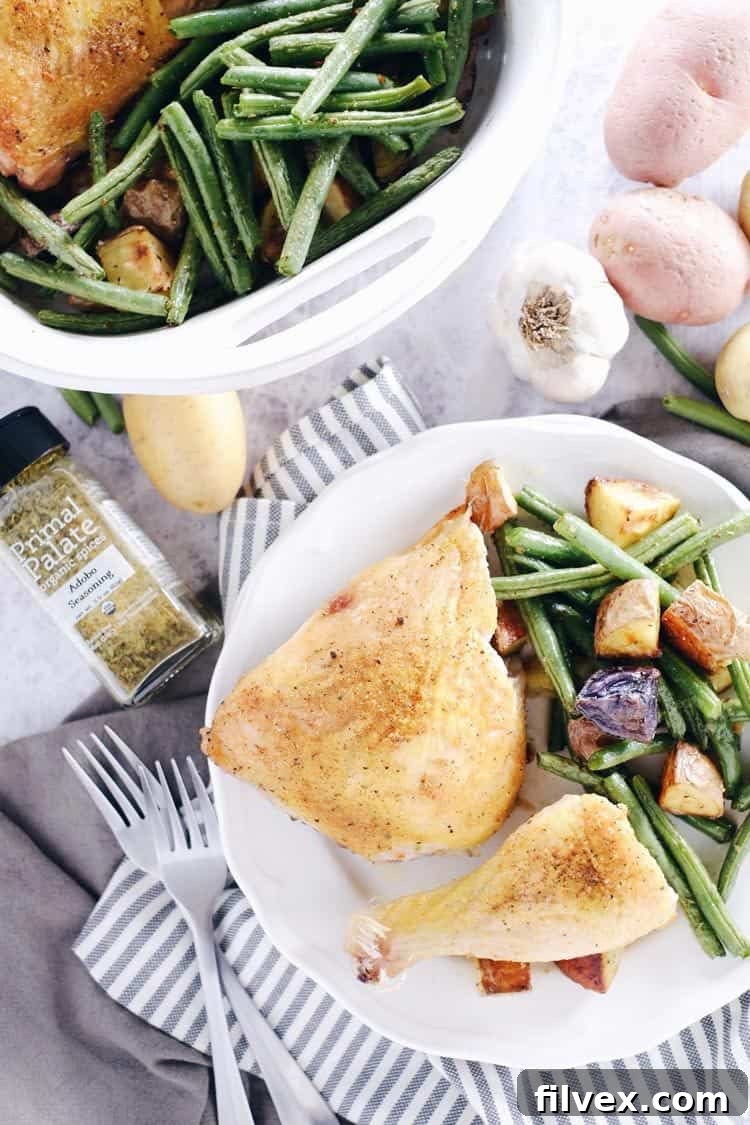 Close-up of One-Pan Herb Roasted Chicken and Veggies on a baking sheet, showing crispy chicken skin and tender vegetables. Paleo, Whole30, Gluten-Free + Dairy-Free.