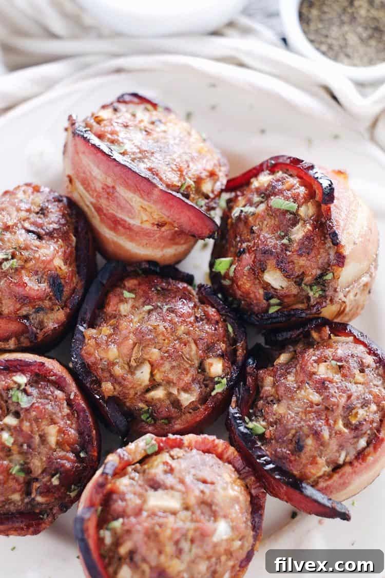Close-up of baked mini bacon wrapped meatloaves in a muffin tin, highlighting their golden-brown perfection.
