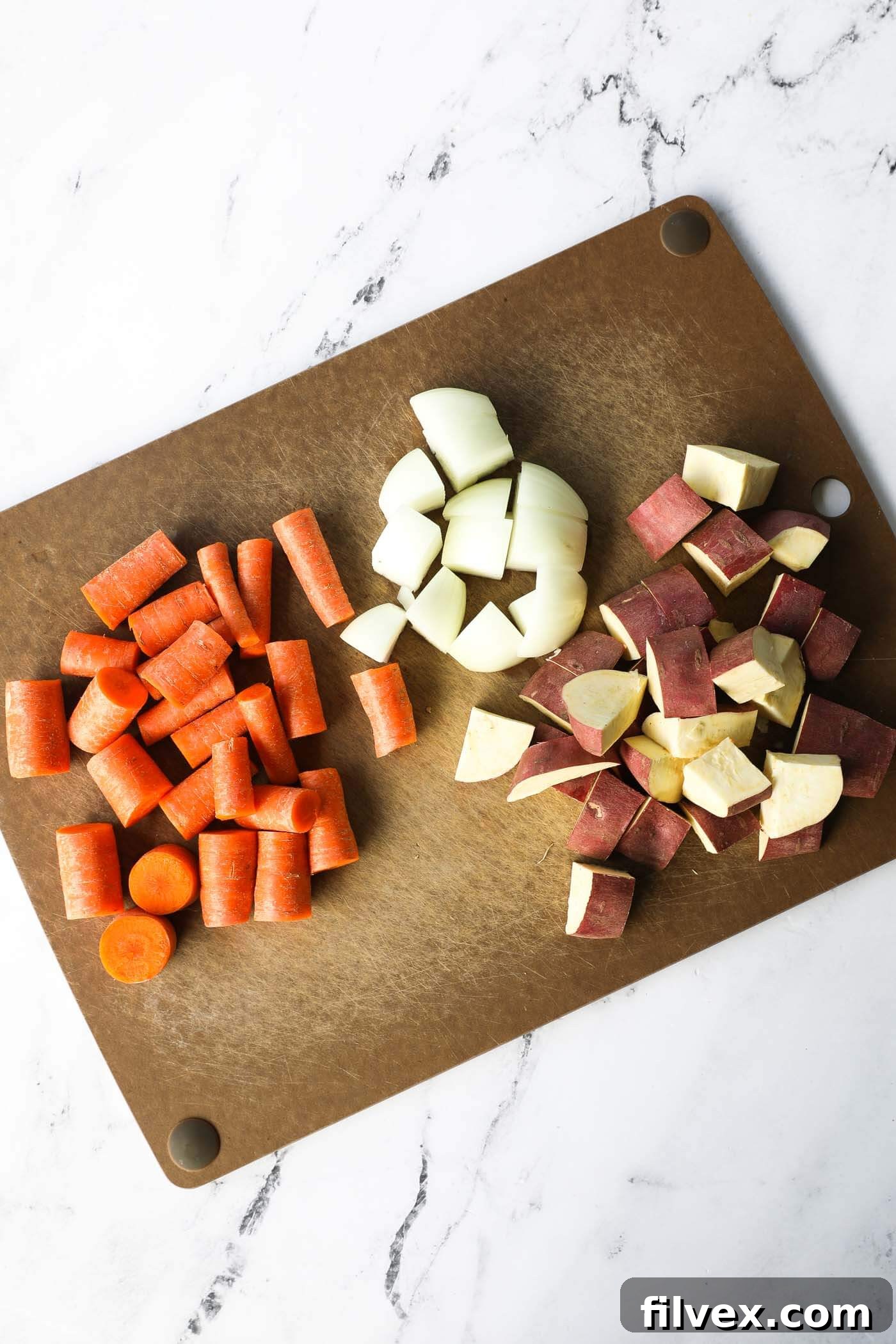 Chopped potato, onions and carrot on a cutting board.