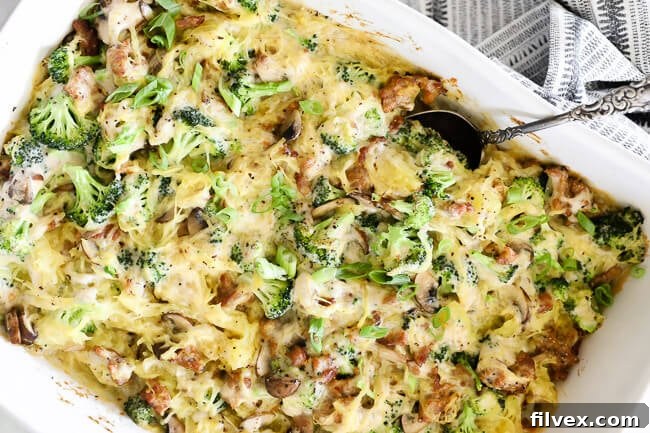 Horizontal image of spaghetti squash casserole in a large dish with serving spoon, showcasing its creamy texture.
