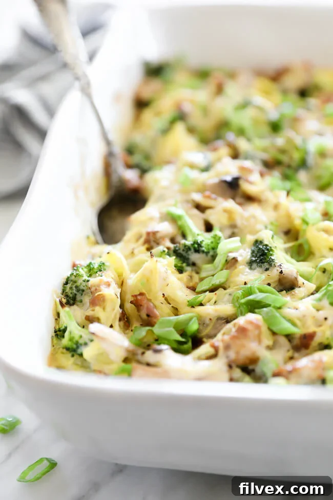 Angled close-up image of a serving of creamy garlic spaghetti squash casserole in a dish with a serving spoon.