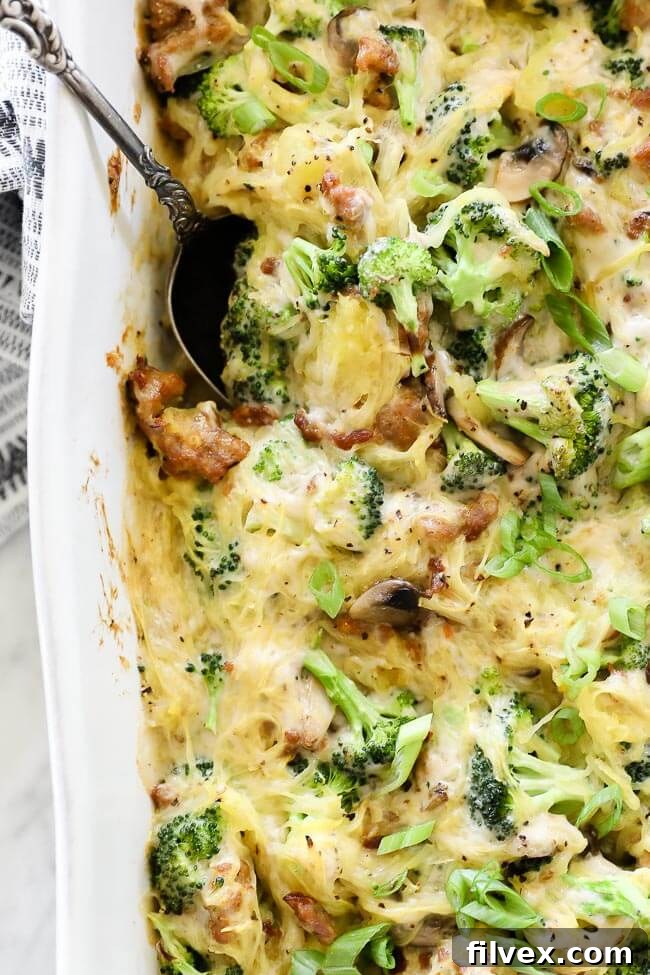 Close-up vertical overhead image of creamy garlic spaghetti squash casserole in a dish with a serving spoon.