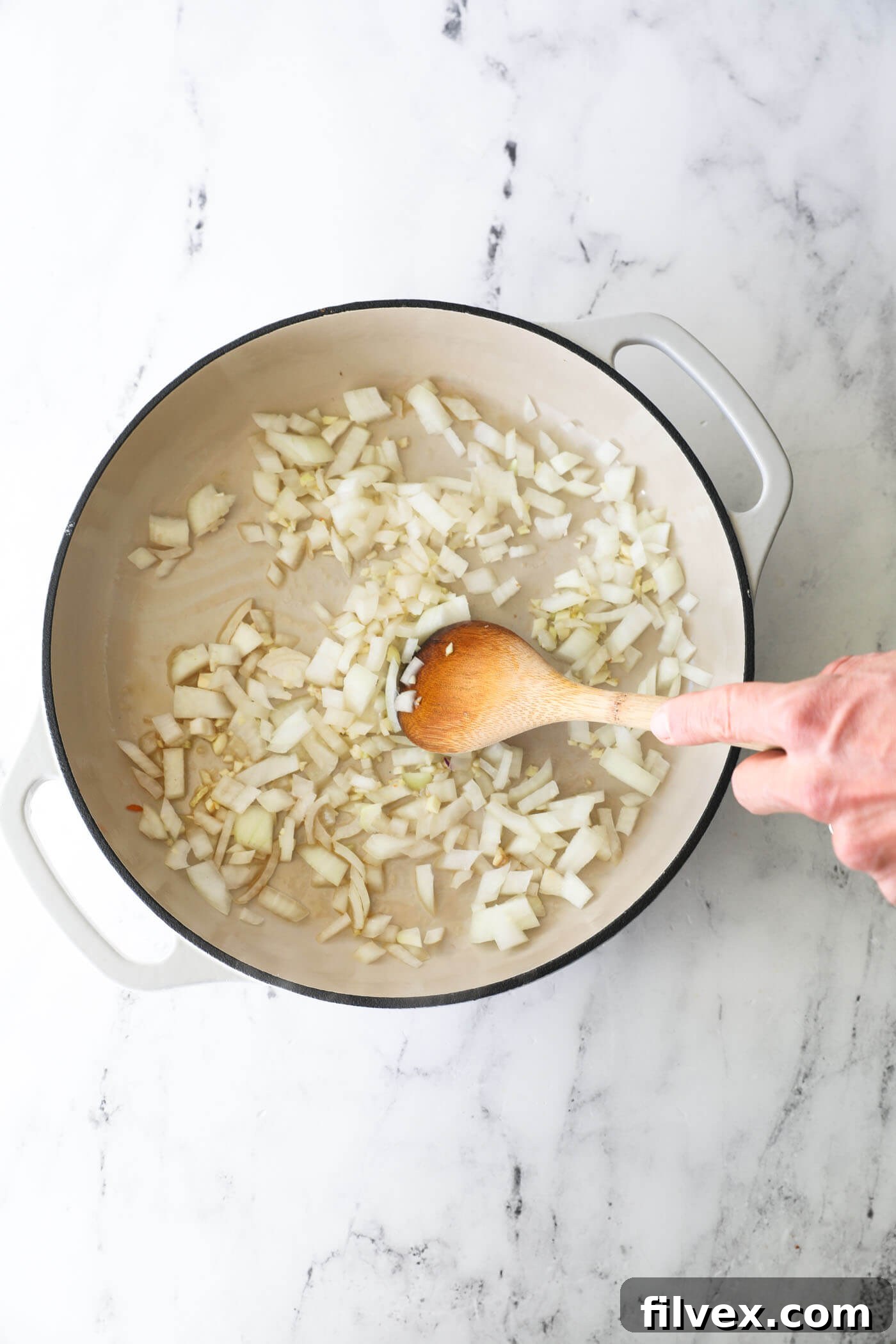 Step 3: Diced onion and minced garlic sautéing in a hot skillet with sesame oil.
