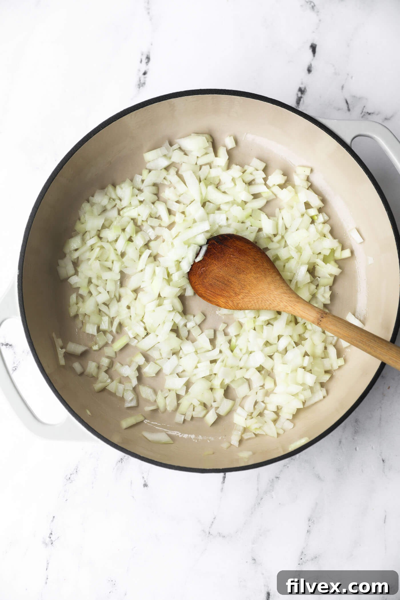 Stirring chopped onion in a skillet while it cooks.