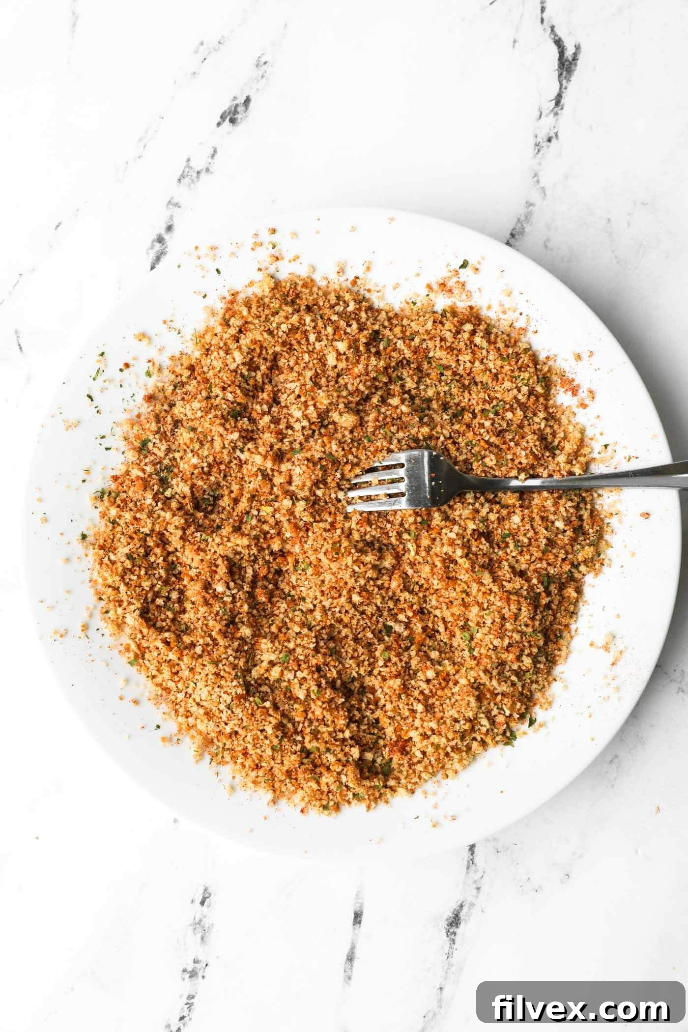 Mixing breadcrumbs and seasonings in a bowl for chicken nuggets