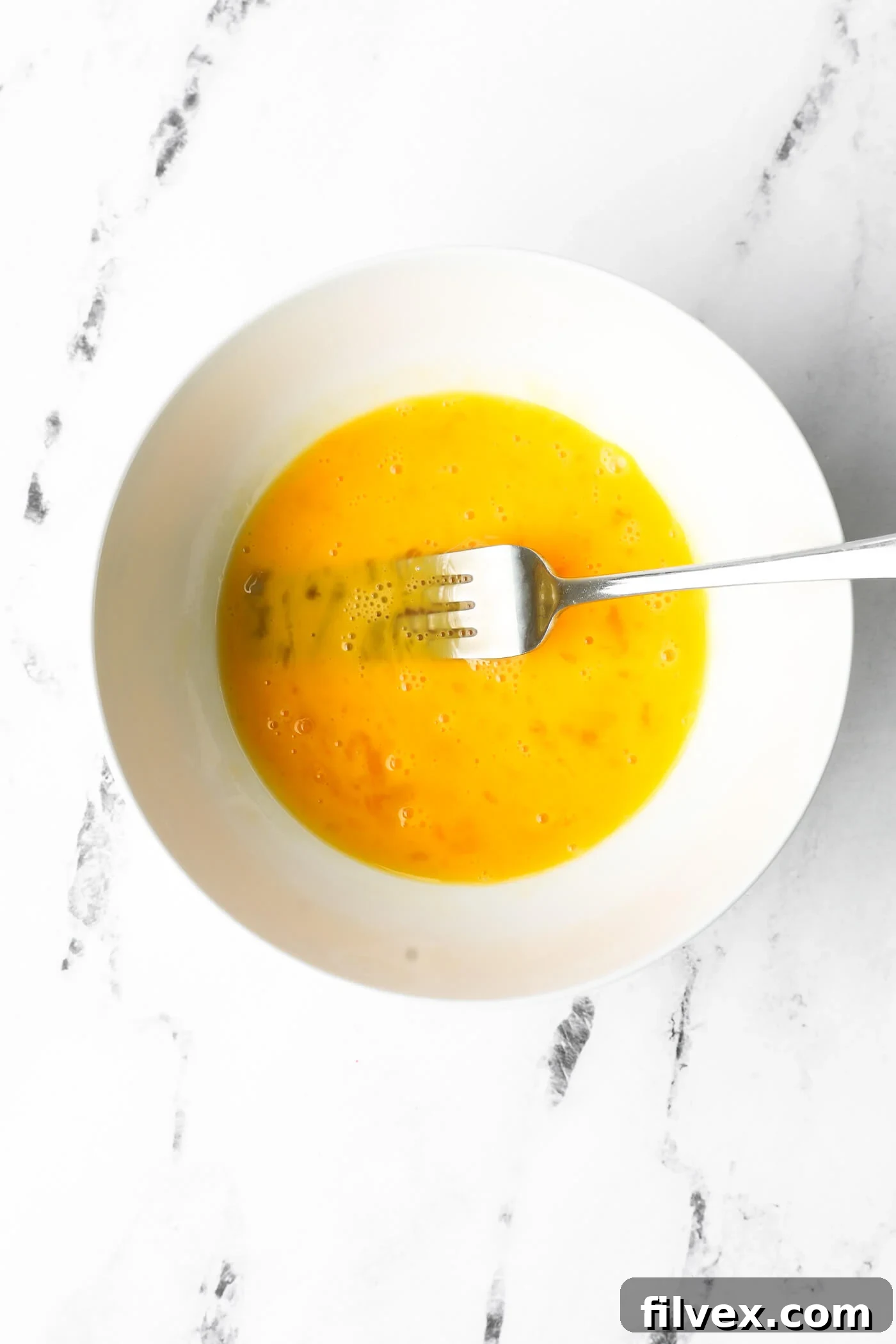 Whisking eggs in a bowl for the chicken nugget coating