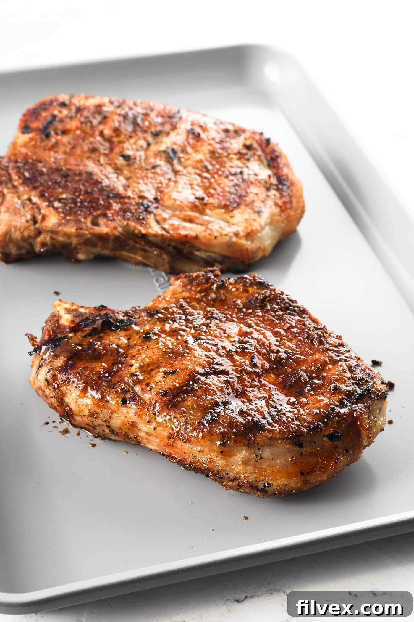 Perfectly grilled pork chops with char marks, removed from the grill and resting on a cutting board.