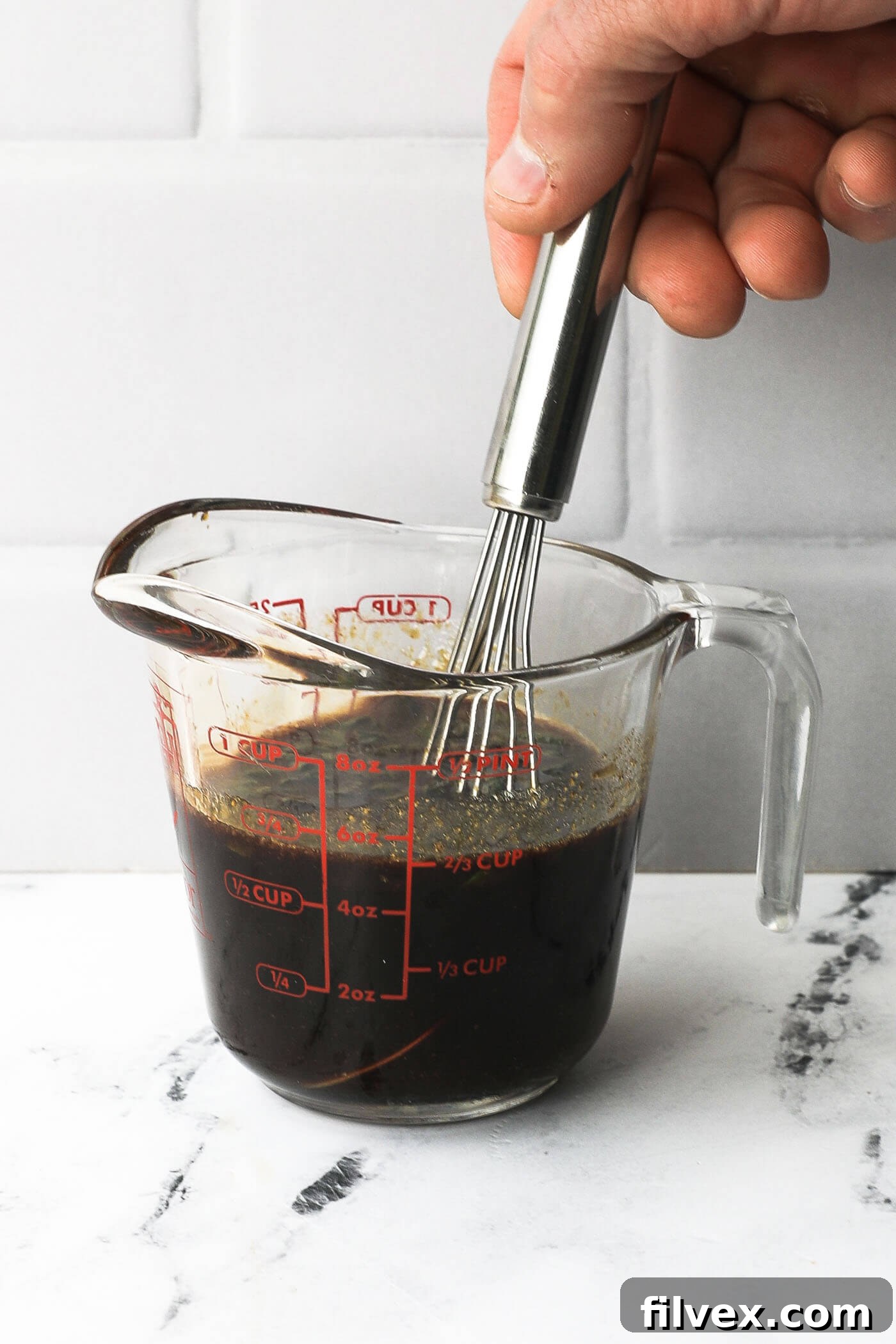 All teriyaki marinade ingredients being stirred together in a glass measuring cup, showcasing the ease of preparation.