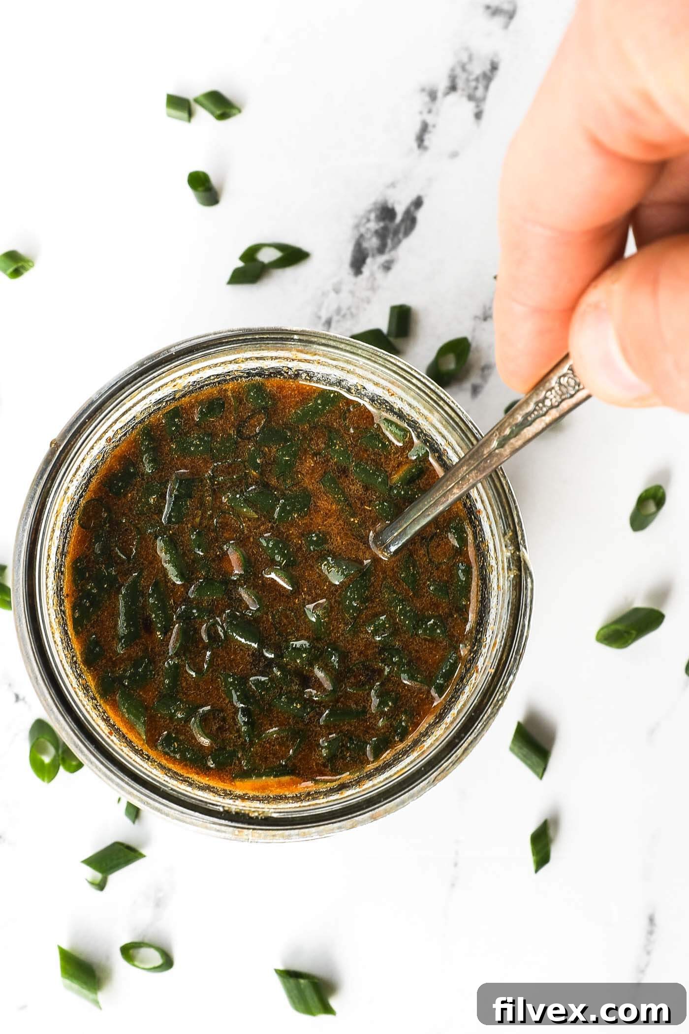 Mixing homemade teriyaki marinade in a glass bowl with a spoon, demonstrating careful preparation.
