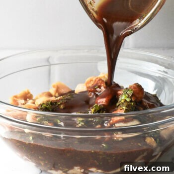 Close up shot of pouring fajita marinade over raw chicken in a glass bowl.