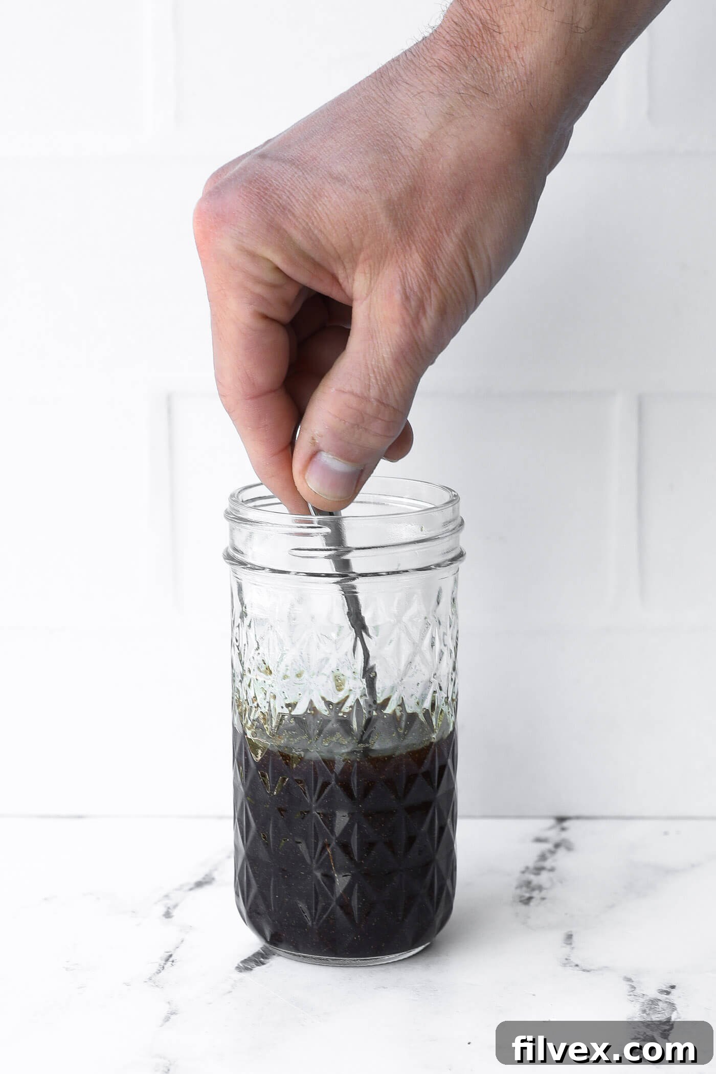 Mixing the balsamic marinade ingredients in a clear glass bowl, showing the vibrant colors.