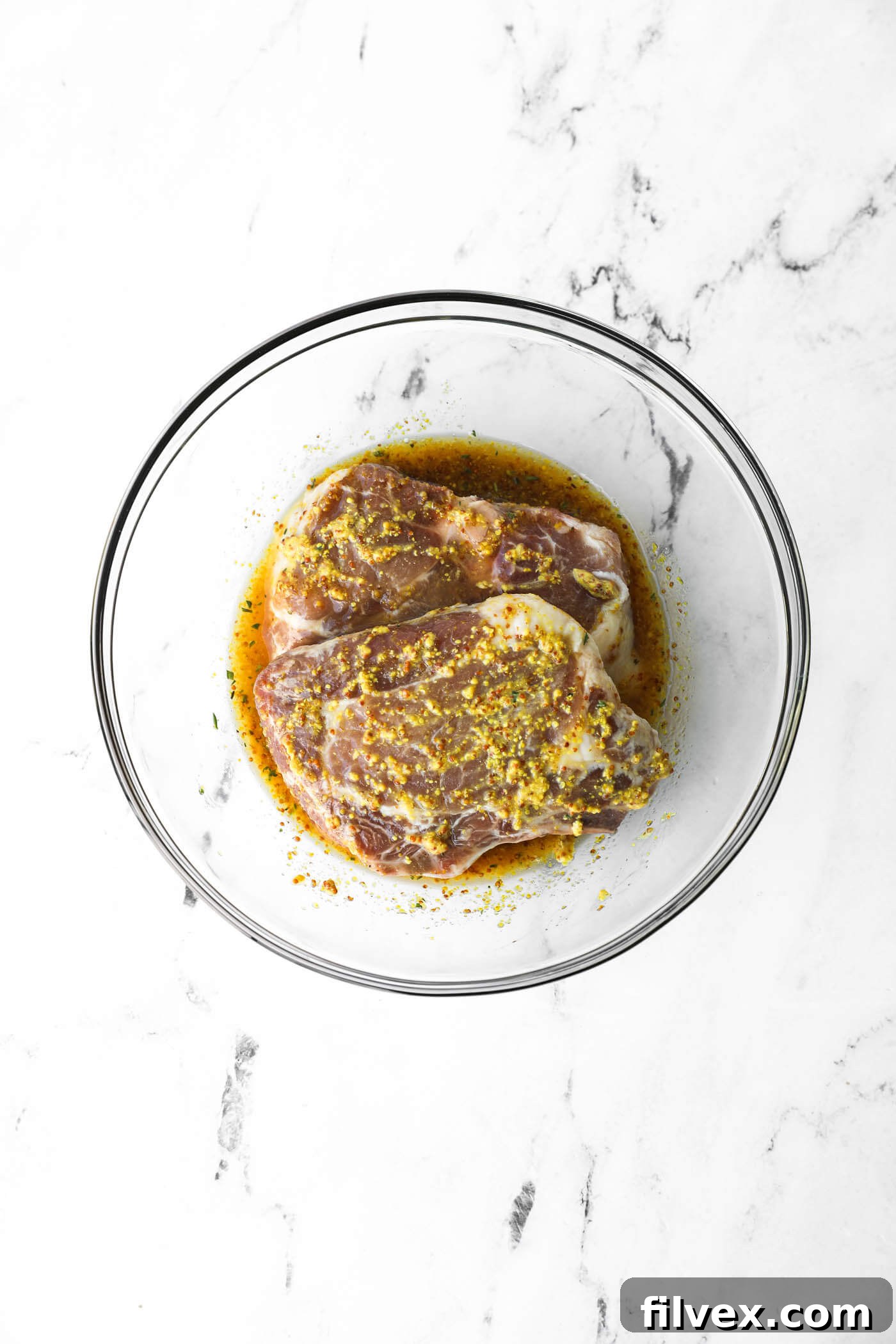 Marinated chicken resting in a bowl, covered and ready for refrigeration.