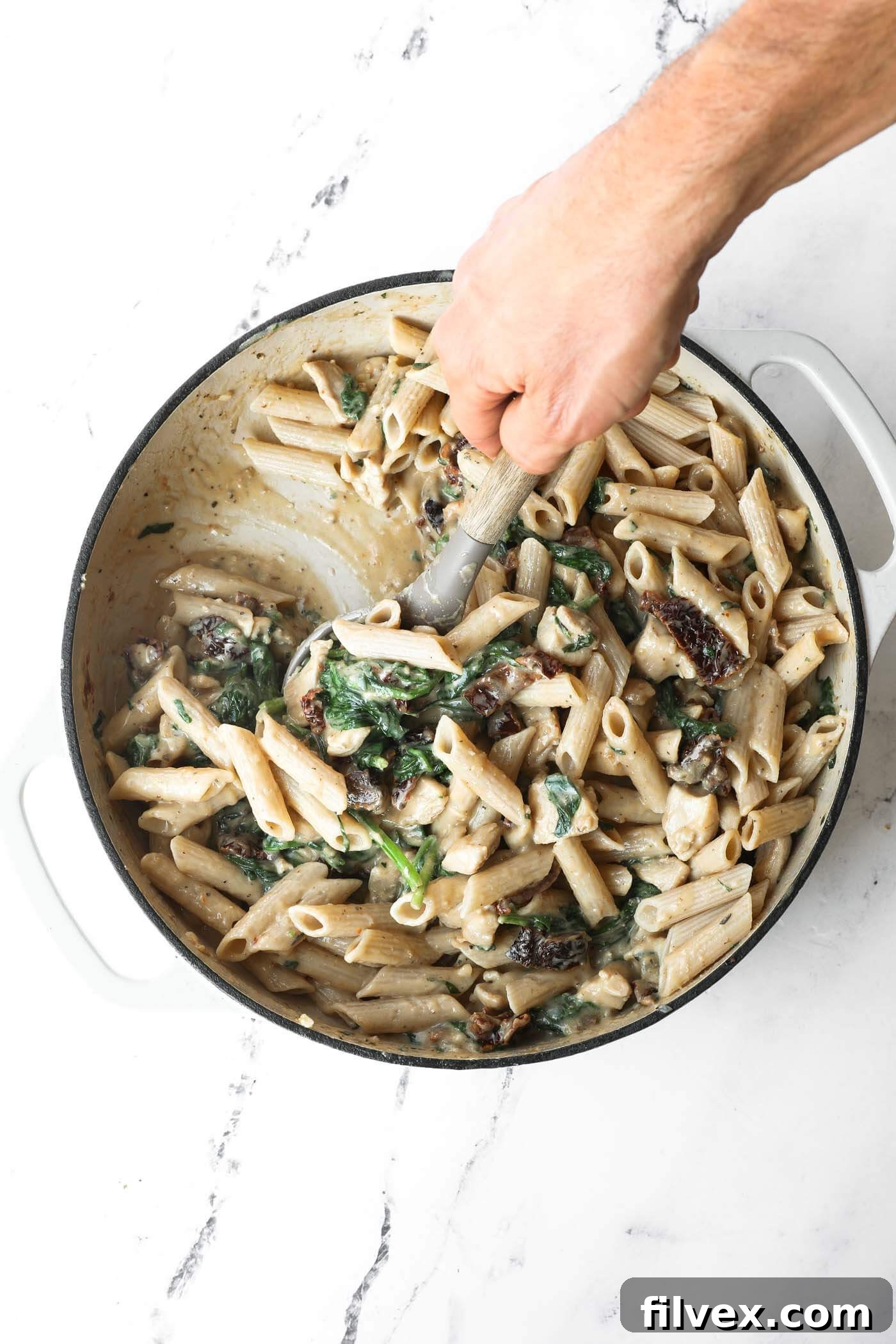 Finished creamy chicken pasta mixed in a skillet, ready to serve.