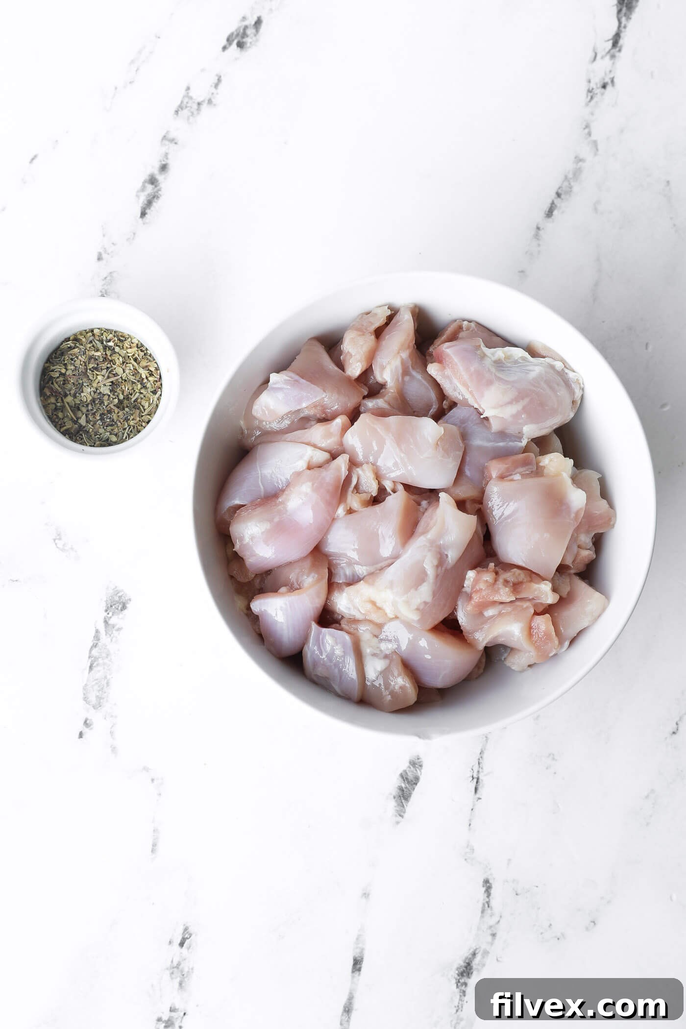 Diced chicken thighs and a bowl of Italian seasoning mix.