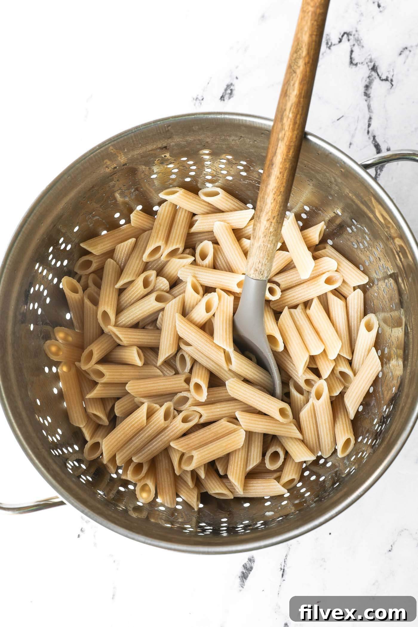 Penne pasta being cooked in a pot of boiling water.