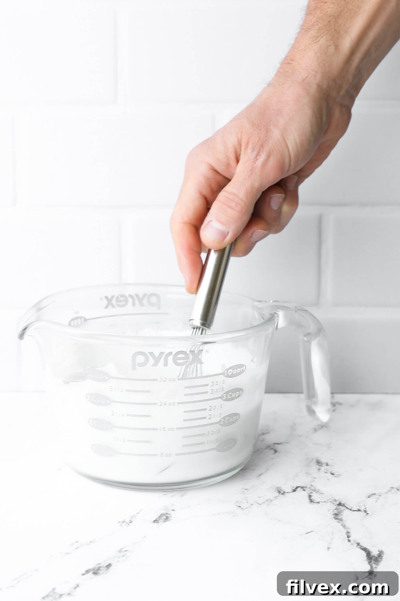 A bowl with whisked heavy cream, chicken broth, and cornstarch.