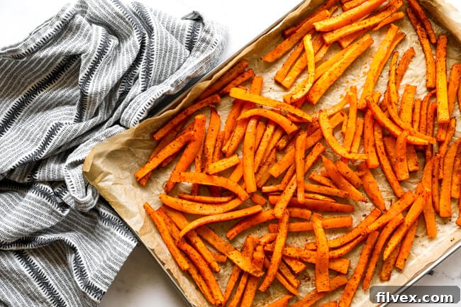 A vibrant overhead shot of golden-brown oven-baked butternut squash fries, perfectly seasoned and ready to be served, highlighting their inviting texture and color.