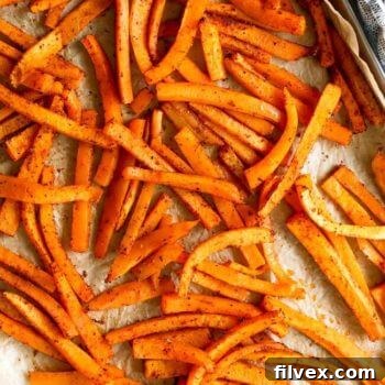 Vertical overhead image of butternut squash fries on a baking sheet, showcasing their golden crispiness.