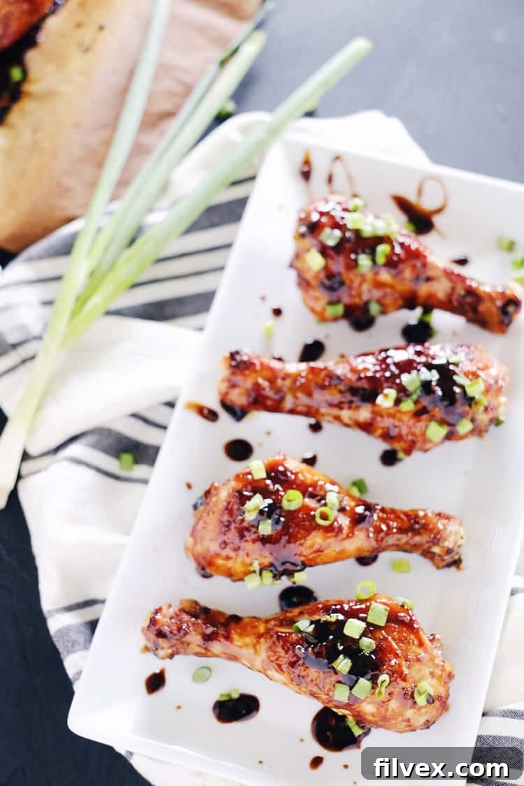 A close-up of two perfectly glazed chicken drumsticks, showing the sticky, dark balsamic sauce clinging to the crispy skin, promising a delightful culinary experience.