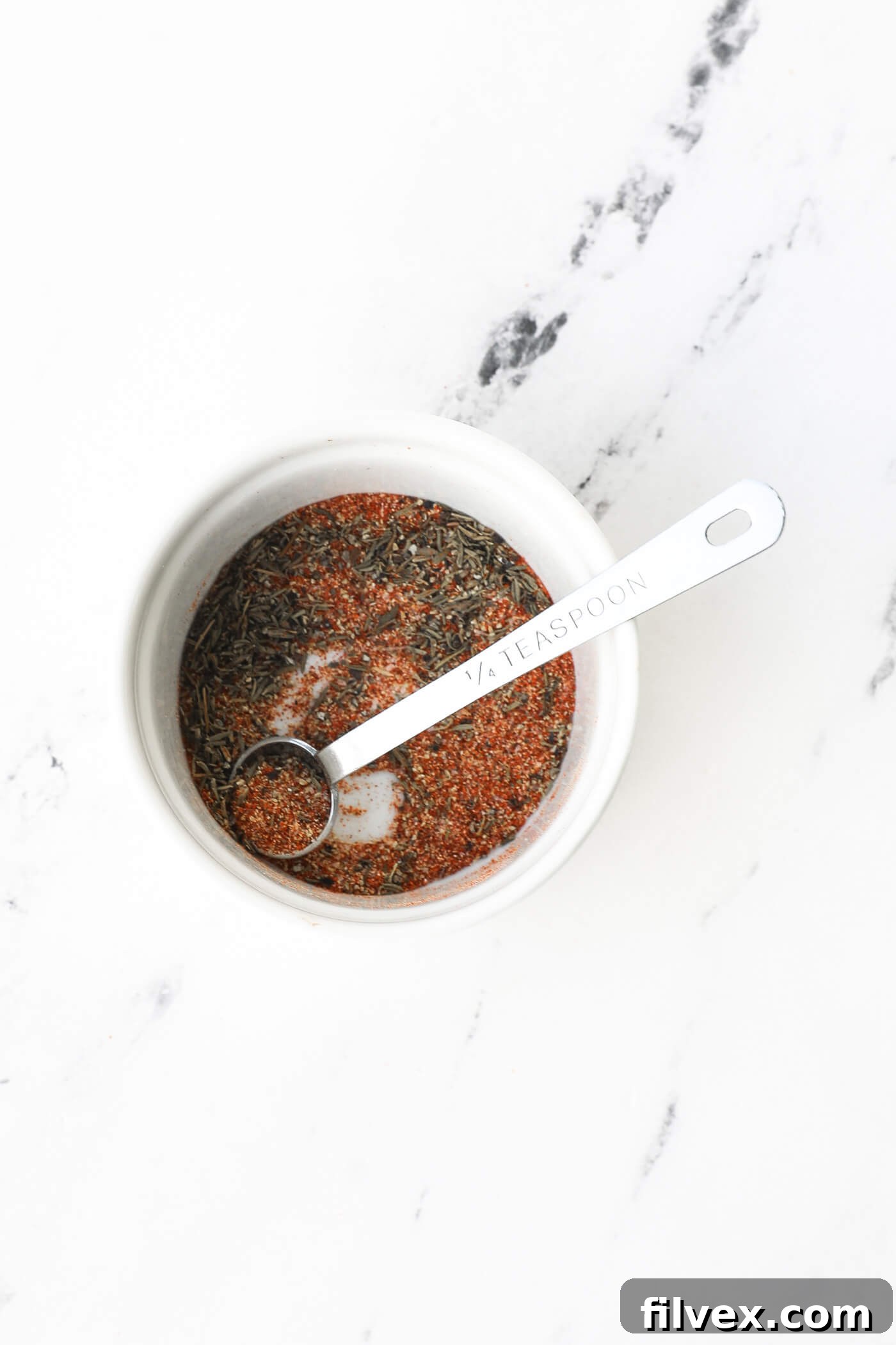 Various seasonings for air fryer shrimp neatly arranged in a ramekin with a measuring spoon, ready for mixing.