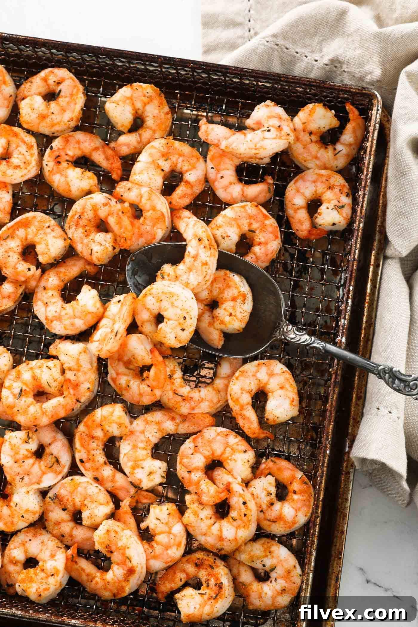 Perfectly cooked air fryer shrimp in the air fryer basket with a serving spoon, illustrating readiness.