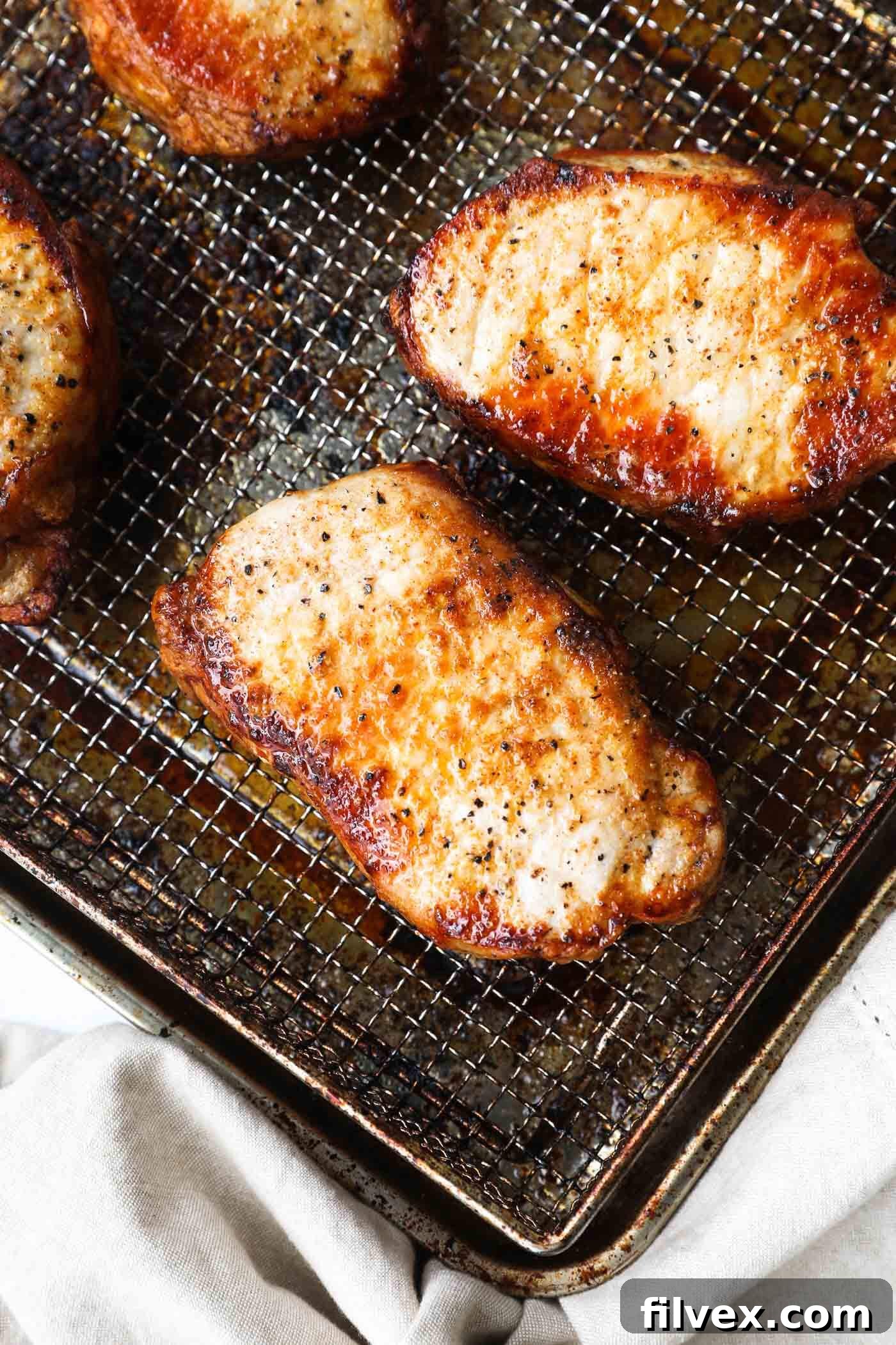 Air fryer frozen pork chops cooking in the air fryer basket, showing a beautiful sear