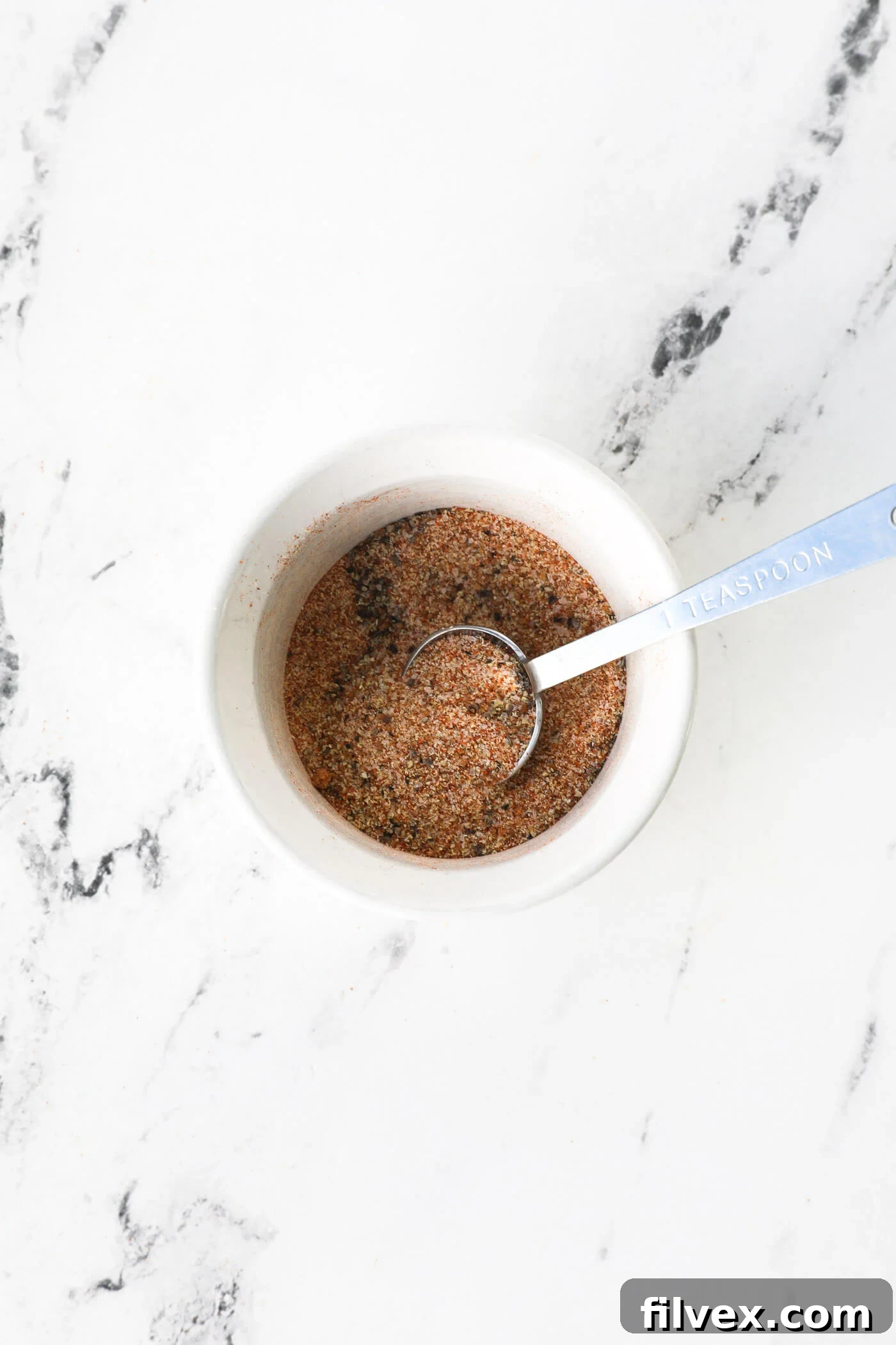 Air fryer being preheated and seasoning ingredients being mixed in a bowl