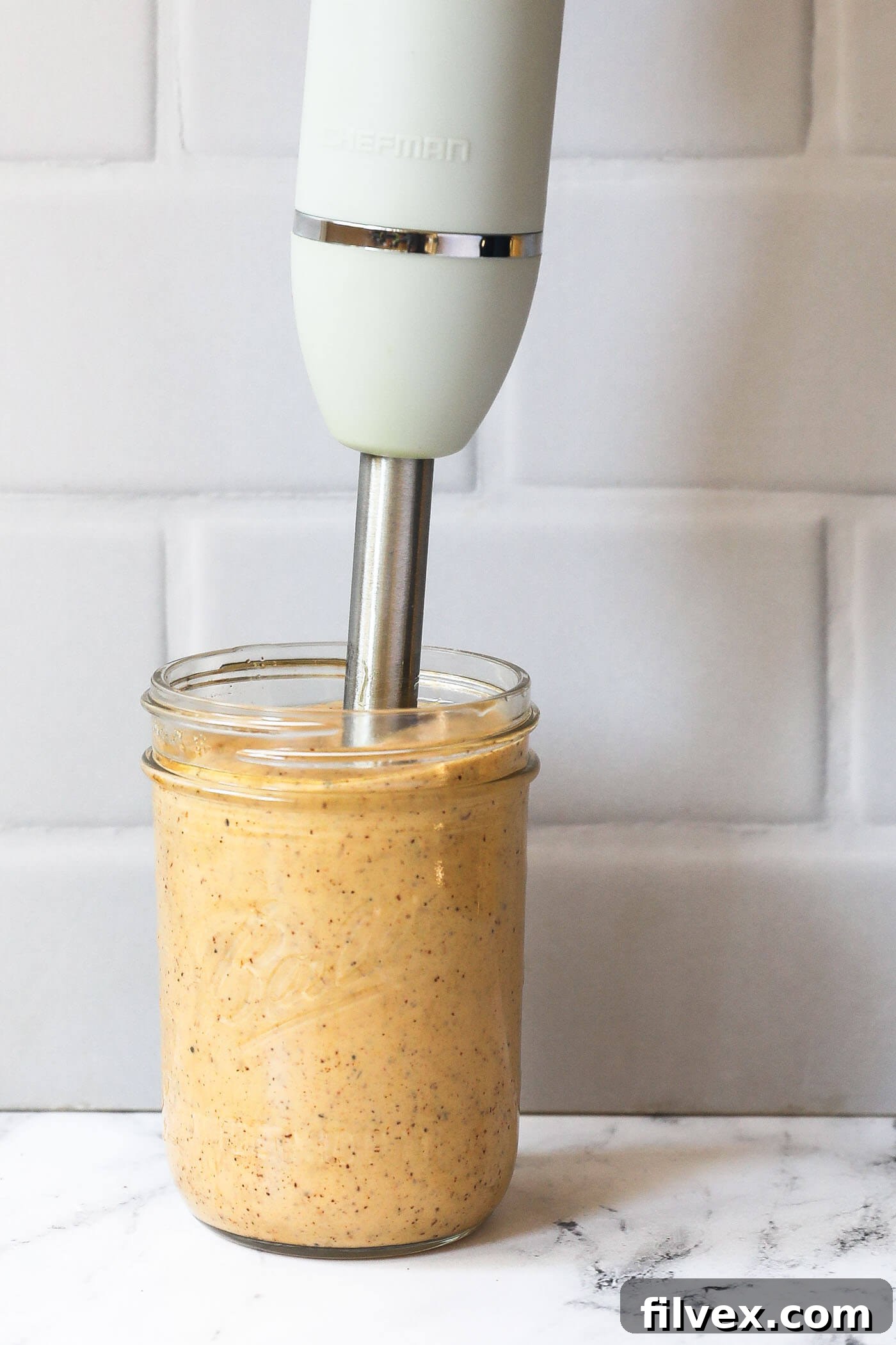 A homemade chili aioli in a mason jar with the immersion blender still in the jar.