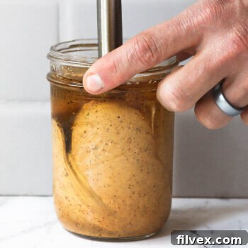 Close up image of sauce ingredients being emulsified in a mason jar.