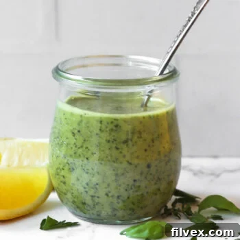 Fresh lemon herb sauce in a jar with a spoon sticking out, ready to be served.