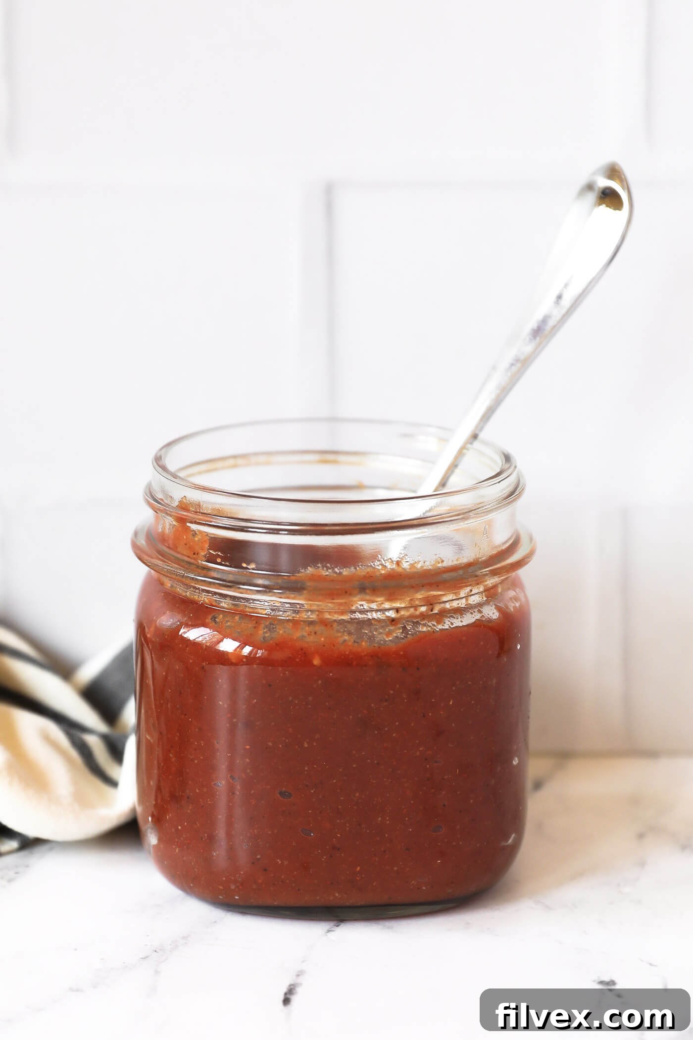 A bottle of homemade chipotle BBQ sauce next to a bowl, ready for serving.