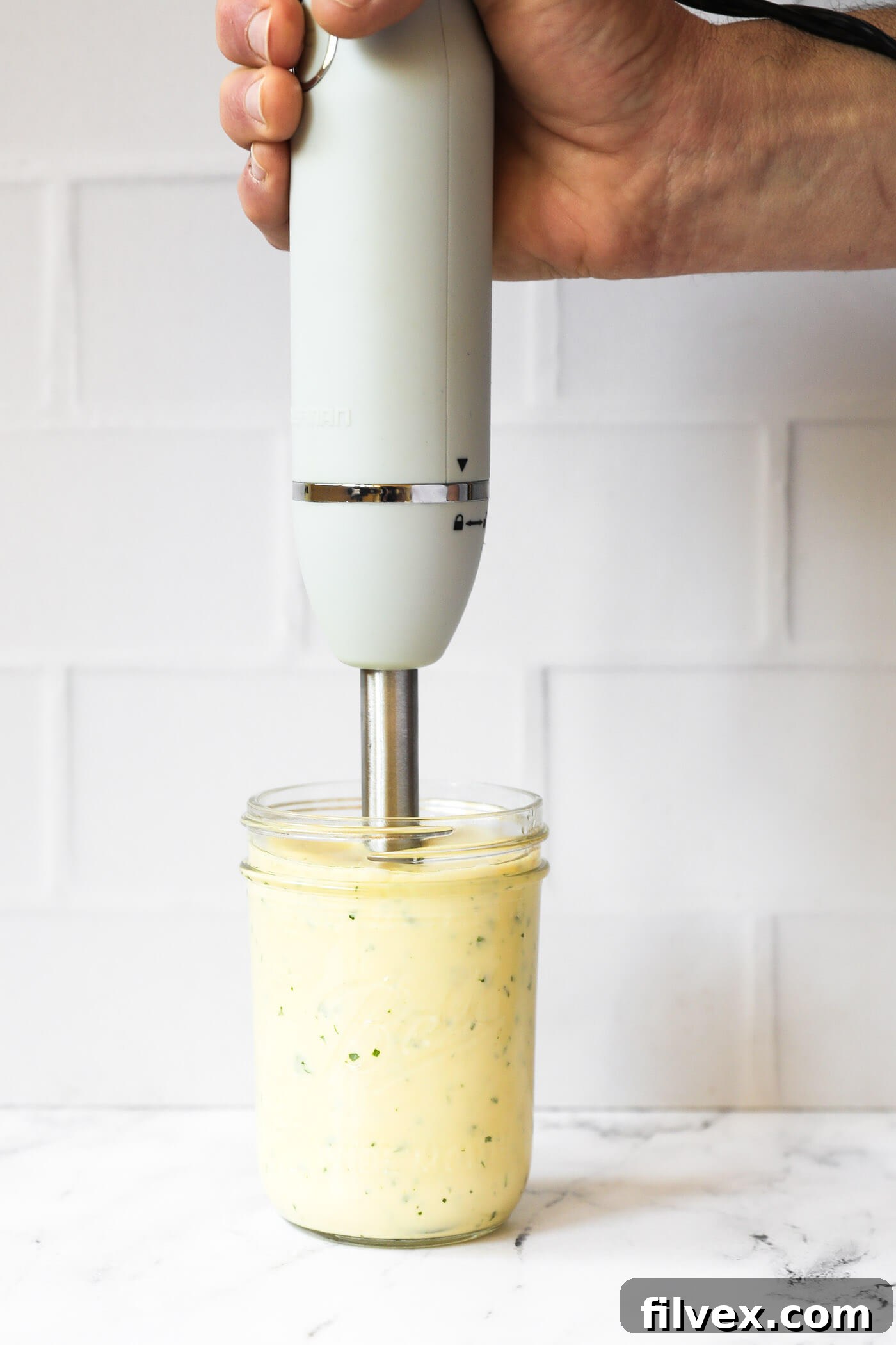 A mason jar filled with perfectly emulsified, thick, and creamy cilantro lime aioli after being blended. The texture is smooth and consistent.
