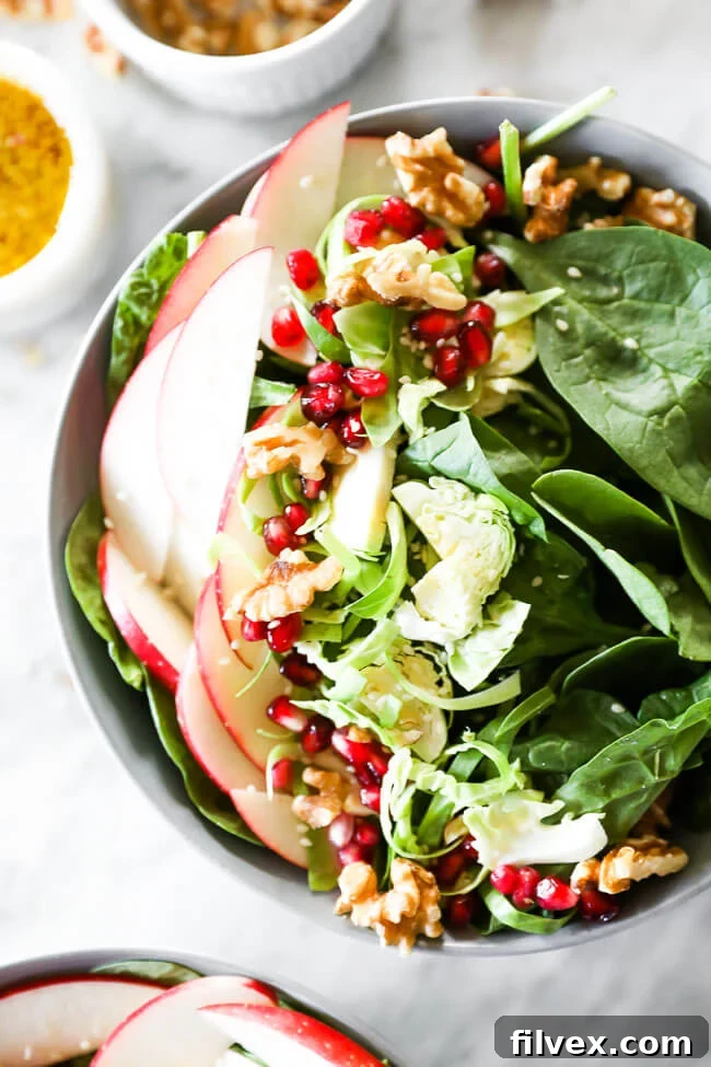 Close-up vertical shot of apple walnut spinach salad, highlighting the fresh ingredients and vibrant colors.