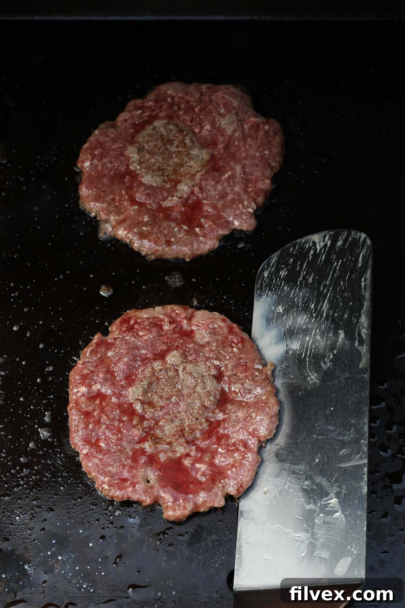 Flipping smash burger patties on a griddle