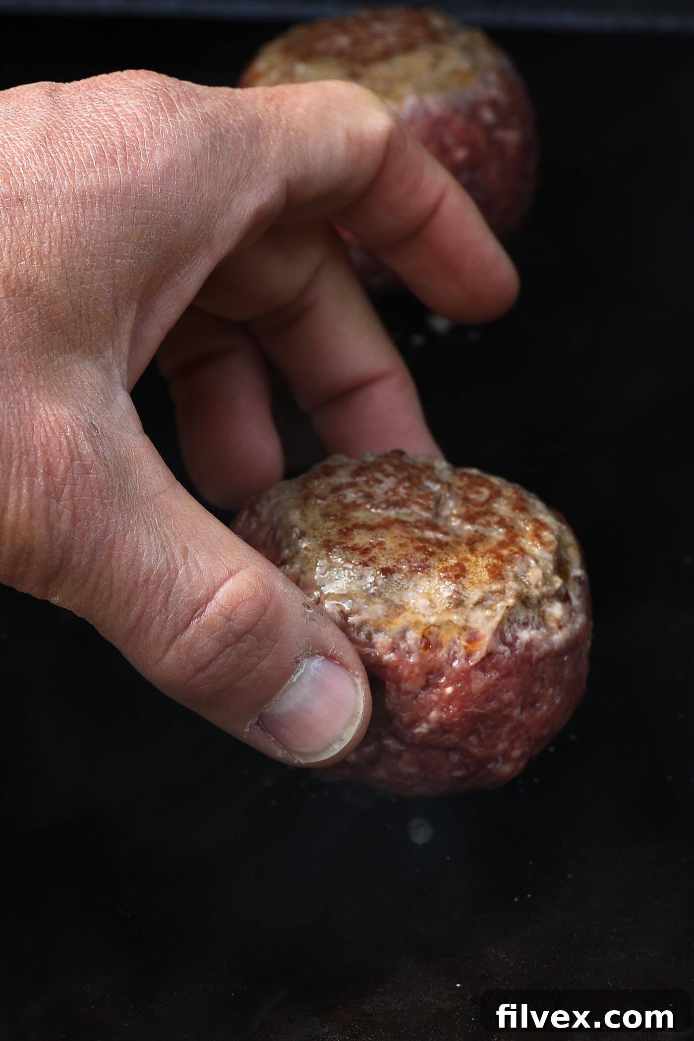Flipping seared beef balls on the griddle